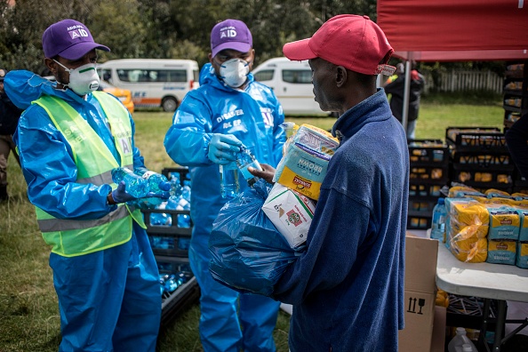 -Un sans-abri reçoit un colis de nourriture après avoir fait la queue avec un groupe de sans-abri dans le parc Innesfree à Johannesburg, le 09 avril 2020. Photo de MARCO LONGARI / AFP via Getty Images.