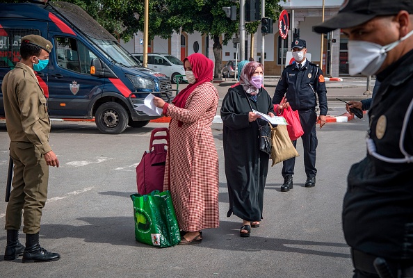 -Les autorités marocaines portant des masques de protection contrôlent les personnes à un barrage routier dans une rue de la capitale Rabat le 9 avril 2020 lors de la crise pandémique du coronavirus. Le port de masques en public est devenu obligatoire au Maroc pour endiguer la propagation des coronavirus, selon un décret officiel. Photo par FADEL SENNA / AFP via Getty Images.