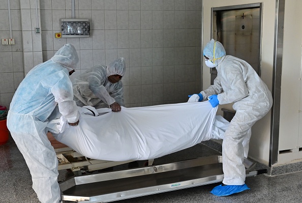 -Des employés soulèvent le corps d'une victime de COVID-19 avant de le charger dans le four du crématorium hindou dans l'émirat du Golfe de Dubaï le 19 avril 2020. Photo de GIUSEPPE CACACE / AFP via Getty Images.