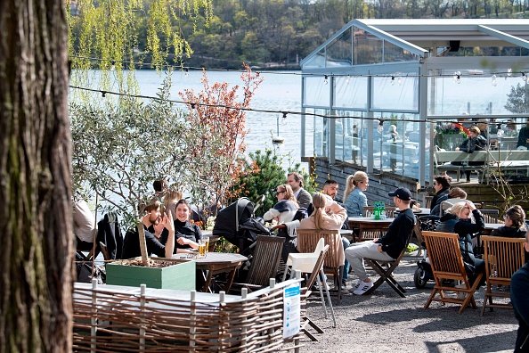 Les gens assis sous le soleil du printemps dans un restaurant en plein air à Stockholm, en Suède, le 26 avril 2020, durant la pandémie de COVID-19. (Photo : JESSICA GOW/TT News Agency/AFP via Getty Images)