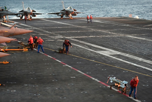 -Des opérateurs de poste de pilotage chargent des bombes sur des avions de combat Rafale à bord du porte-avions français Charles-de-Gaulle opérant dans l'est de la Méditerranée le 9 décembre 2016. Photo STEPHANE DE SAKUTIN / AFP via Getty Images.