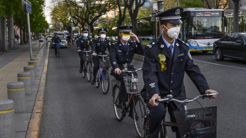 Des officiers chinois circulent ensemble à vélo dans une zone commerciale de Pékin, en Chine, le 22 avril 2020. (Kevin Frayer/Getty Images)