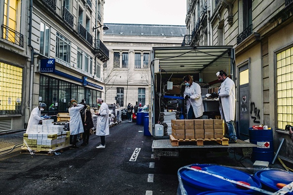 Des employés de la pharmacie Delpech s’activent à l’extérieur de l’officine qui produit des milliers de litre de solution hydroalcoolique par jour. Crédit : LUCAS BARIOULET/AFP via Getty Images.