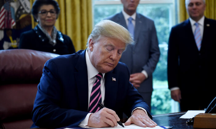 Le président américain Donald Trump signe un programme de protection des salaires et une loi de bonification des soins de santé, dans le Bureau ovale de la Maison-Blanche à Washington, le 24 avril 2020. (Olivier Douliery/AFP via Getty Images)