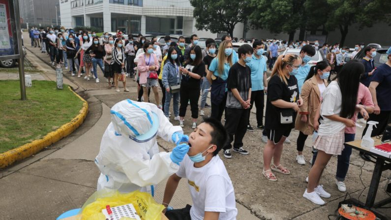 Le 15 mai 2020, un professionnel de santé prélève un échantillon sur un membre du personnel de l'usine de moniteurs informatiques AOC afin de le tester pour le Covid-19 à Wuhan, dans la province centrale du Hubei, en Chine. (STR/AFP via Getty Images) 