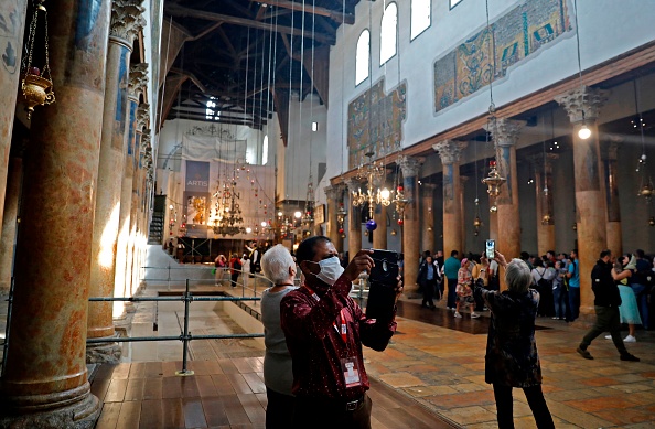 -Des personnes portant des masques visitent l'église de la Nativité, vénérée comme le lieu de naissance de Jésus-Christ, dans la ville cisjordanienne de Bethléem, le 5 mars 2020. Photo par AHMAD GHARABLI / AFP via Getty Images.