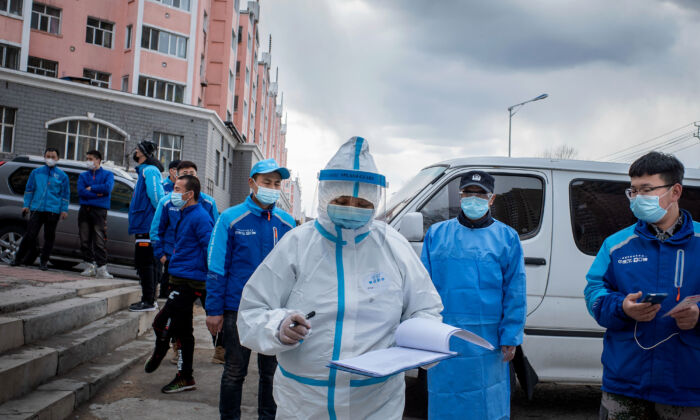 Le 24 avril 2020, un membre du personnel médical vérifie des notices devant les employés de la livraison de nourriture qui font la queue pour passer leur test d'acide nucléique dans un centre de services de santé à Suifenhe, en Chine. (STR/AFP via Getty Images)