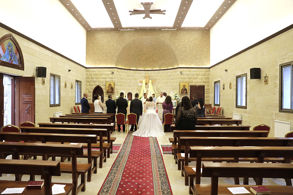 -Maya Khadra et Rakan Ghossein se tiennent devant un prêtre lors de leur mariage à l'église Notre-Dame d'Assistance dans le village de Shemlan au sud de Beyrouth le 25 avril 2020. Photo par ANWAR AMRO / AFP via Getty Images.