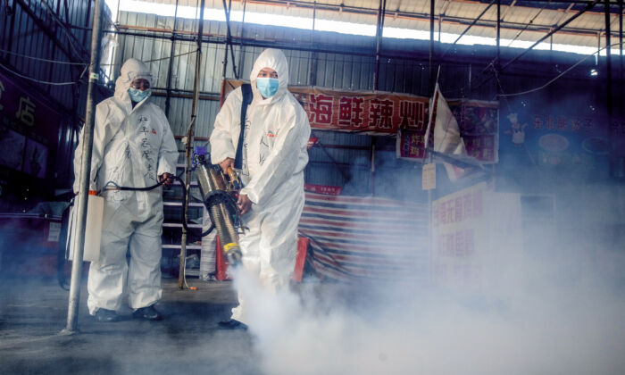 Deux volontaires pulvérisent du désinfectant sur un marché de la ville frontalière de Suifenhe, dans la province du Heilongjiang, au nord-est de la Chine, le 6 mai 2020. (STR/AFP via Getty Images)