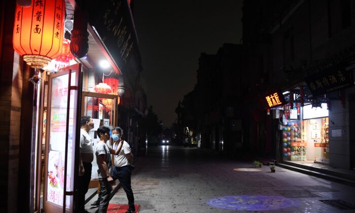 Un groupe d'hommes prend des photos alors que le ciel s'assombrit en milieu d'après-midi, à l'approche d'un orage dans une ruelle au sud de la place Tian'anmen à Pékin, lors de la cérémonie d'ouverture de la Conférence consultative politique du peuple chinois (CPPCC) à Pékin, en Chine, le 21 mai 2020. (GREG BAKER/AFP via Getty Images)