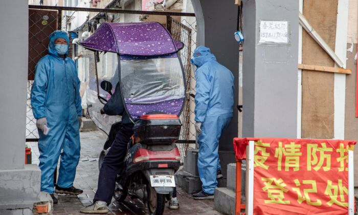 Des bénévoles vérifient l'identité d'un résident à l'entrée d'un complexe résidentiel dans la ville de Jilin, en Chine, le 22 mai 2020. (STR/AFP via Getty Images)