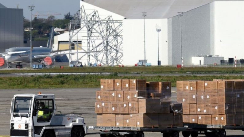 Un travailleur transporte le fret déchargé d'un avion Airbus A350-1000 transportant des masques faciaux de la Chine vers l'Europe, à l'aéroport Toulouse-Blagnac, dans le sud de la France, le 5 avril 2020.  (Photo by REMY GABALDA/AFP via Getty Images)