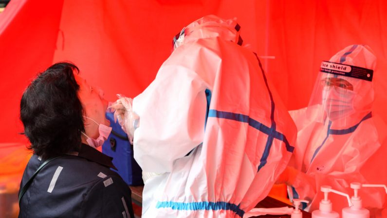 Un professionnel de la santé prélève un échantillon par frottis sur un habitant pour le soumettre à un test de dépistage du virus du PCC dans une rue de Mudanjiang, en Chine, le 3 juin 2020. (STR/AFP via Getty Images)