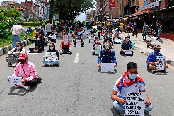 -Les manifestants qui maintiennent une distance sociale tiennent des pancartes lors d'une manifestation contre la gestion par le gouvernement de la lutte contre le coronavirus COVID-19, à Katmandou le 13 juin 2020. Photo de PRAKASH MATHEMA / AFP via Getty Images.