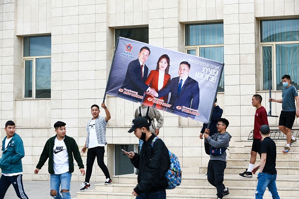 -Des sympathisants tiennent une bannière avec des candidats du Parti du peuple mongol. Les Mongols se rendront aux urnes le 24 juin pour élire un nouveau parlement. Photo de BYAMBASUREN BYAMBA-OCHIR / AFP via Getty Images.