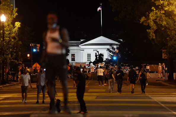 -Des manifestants se rassemblent devant la Maison Blanche et la statue équestre de l'ancien président américain Andrew Jackson, protégée par une clôture et des blocs de béton à Washington, DC le 26 juin 2020.  Le président américain Donald Trump a signé un exécutif qui ordonne de s'engager à engager des poursuites pour les manifestants qui vandalisent les monuments commémoratifs publics. Photo par OLIVIER DOULIERY / AFP via Getty Images.