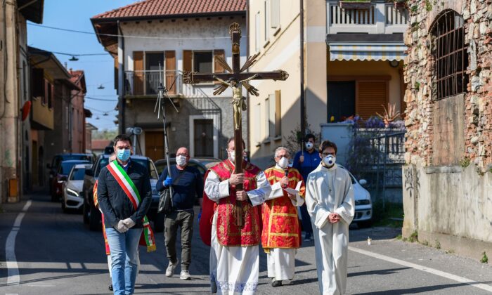 Le curé de l'église Santa Maria Assunta de Pontoglio, Don Giovanni Cominardi (C), est escorté par le maire de Pontoglio, Alessandro Seghezzi (L), lors d'une procession du Via Crucis (Chemin de croix) dans le cadre des célébrations du Vendredi Saint à Pontoglio, en Italie, le 10 avril 2020. (Miguel Medina /AFP via Getty Images)