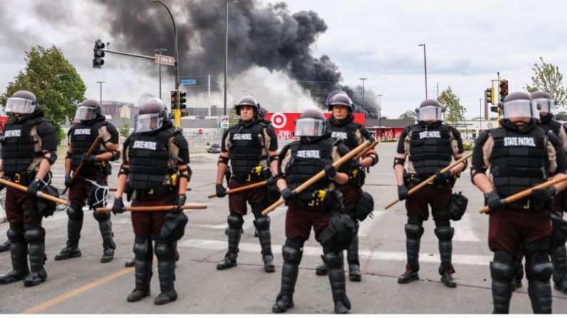 La police d'État monte la garde alors que la fumée s'échappe des bâtiments qui continuent de brûler à la suite d'une nuit de protestations et de violence après la mort de George Floyd, à Minneapolis (Minnesota), le 29 mai 2020. (Charlotte Cuthbertson/The Epoch Times)