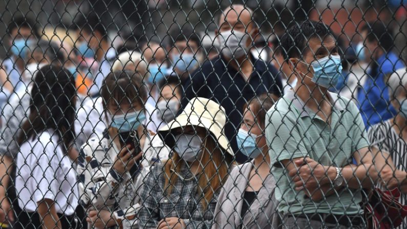 Des gens se rassemblent dans un espace extérieur pour effectuer un test par écouvillonnage lors du test de masse pour le Covid-19 à Pékin, en Chine, le 23 juin 2020. (NOEL CELIS/AFP via Getty Images)