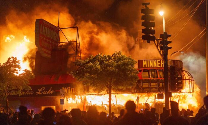 Des manifestants rassemblés devant un magasin d'alcool en flammes près du troisième commissariat de police de Minneapolis (Minnesota), États-Unis, le 28 mai 2020. (Kerem Yucel/AFP via Getty Images)