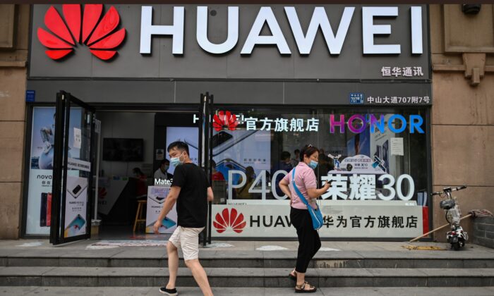 Des personnes portant des masques marchent devant un magasin Huawei à Wuhan, dans la province de Hubei, en Chine, le 26 mai 2020. (HECTOR RETAMAL/AFP via Getty Images)