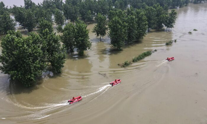 Les pompiers patrouillent avec des bateaux dans une zone inondée près du fleuve Yang-Tzé à Zhenjiang, dans la province chinoise du Jiangsu oriental, le 20 juillet 2020. (STR/AFP via Getty Images)