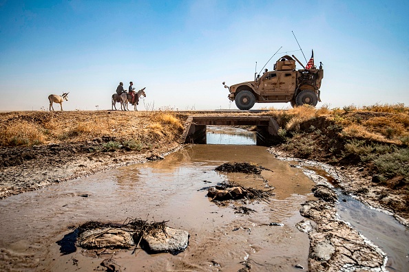  -Des jeunes montés à dos d'âne traversent un ruisseau pollué par une marée noire près du village de Sukayriyah, le 19 juillet 2020. - Photo par DELIL SOULEIMAN / AFP via Getty Images.