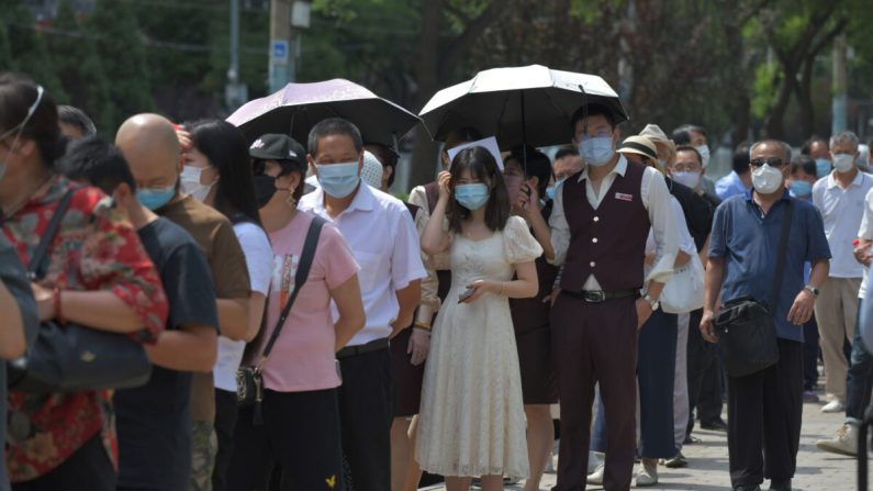 Des personnes font la queue pour effectuer des tests Covid-19 par écouvillonnage dans une station d'essai à Pékin, en Chine, le 30 juin 2020. (GREG BAKER/AFP via Getty Images)