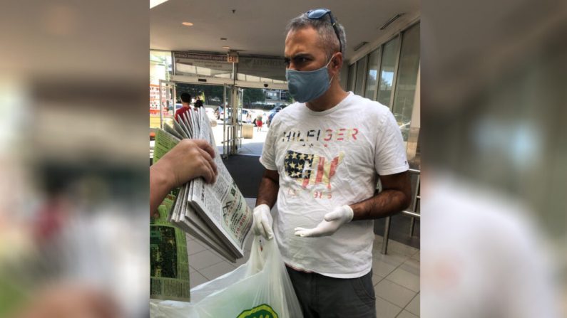 Un homme est confronté à un membre du personnel du journal Epoch Times (non vu dans le cadre) en train de prendre plus de 10 exemplaires du journal Epoch Times à Toronto le 4 juillet 2020. (The Epoch Times)