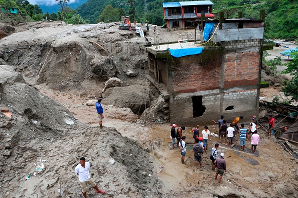 -Illustration- Des résidents et des secouristes inspectent la zone à l'extérieur d'une maison endommagée par un glissement de terrain en raison de fortes pluies dans un village du district de Sindhupalchok. Photo par Niroj CHAOULAGAIN / AFP via Getty Images.