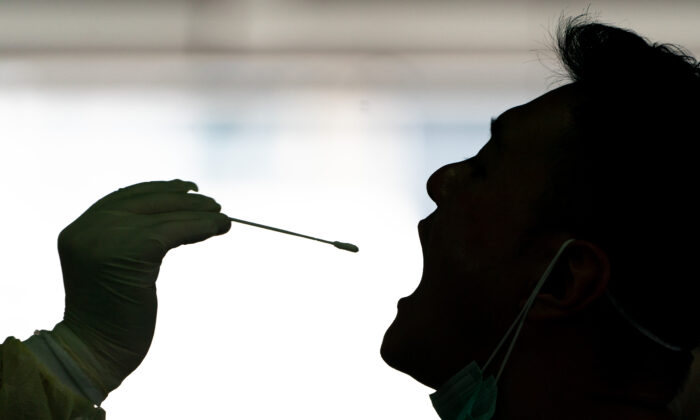 Un professionnel de la santé prélève un échantillon sur un chauffeur de taxi pour le test Covid-19 dans une station de dépistage improvisée à Hong Kong le 24 juillet 2020. (Anthony Kwan/Getty Images)