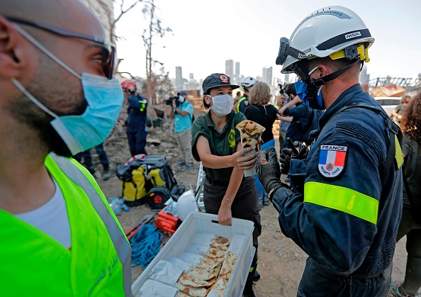 -Un sauveteur de la défense civile libanaise offre de la nourriture à un secouriste français lors d'un effort de recherche dans le port de Beyrouth le 7 août 2020, trois jours après une explosion massive qui a secoué la capitale libanaise. Photo JOSEPH EID/AFP via Getty Images.