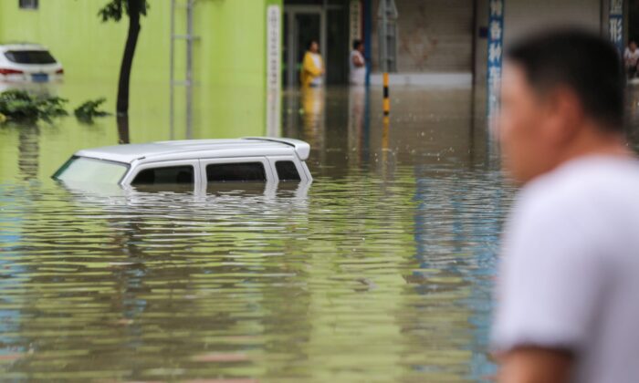 Un homme regarde les véhicules bloqués dans une rue inondée après les fortes pluies qui ont frappé la région de Linyi, dans la province du Shandong, à l'est de la Chine, le 14 août 2020. (STR/AFP via Getty Images)