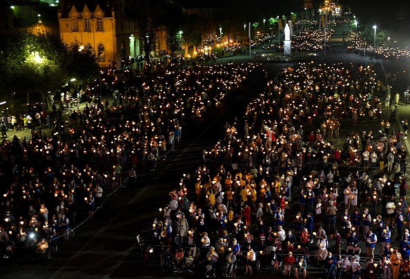 -Des fidèles portant des masques faciaux assistent à la 147e messe de pèlerinage de l'Assomption à Lourdes, le 14 août 2020. Photo de GEORGES GOBET / AFP via Getty Images.