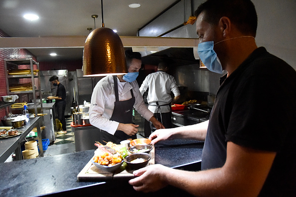 -Un serveur et un cuisinier portent des masques de protection alors qu'ils travaillent dans un restaurant à Alger le 19 août 2020. Photo de RYAD KRAMDI / AFP via Getty Images.