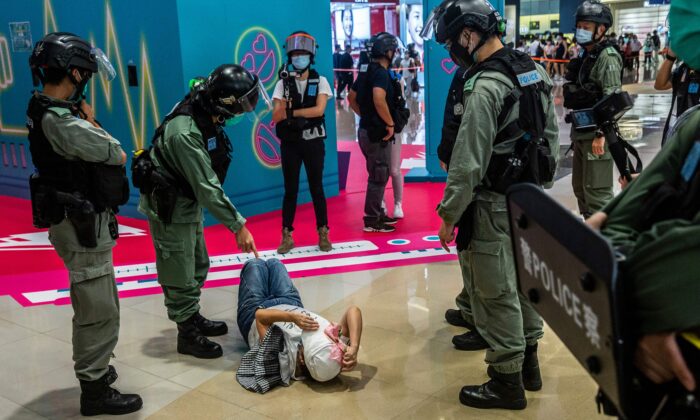 Un agent de la police anti-émeute (2e à G) montre du doigt une femme allongée après avoir été fouillée lors d'une manifestation dans un centre commercial de Hong Kong le 6 juillet 2020, en réponse à la nouvelle loi sur la sécurité nationale de Pékin. (Isaac Lawrence/AFP via Getty Images)