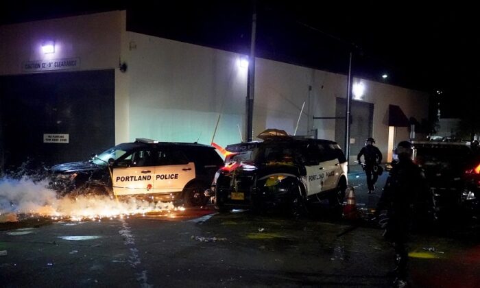 Une grenade fumigène s'enflamme sous une voiture de police vandalisée près d’un commissariat de police lors d'une manifestation à Portland, États-Unis, le 22 août 2020. (Nathan Howard/Getty Images)