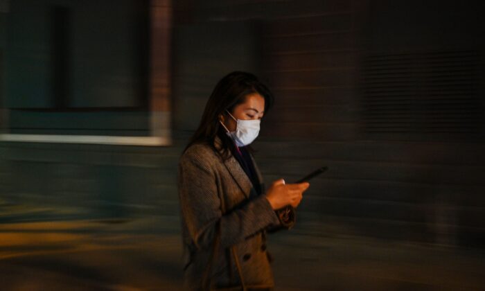 Une femme vérifie son téléphone portable à Shanghai, en Chine, le 17 mars 2020. (HECTOR RETAMAL/AFP via Getty Images)