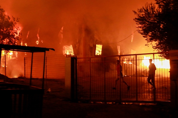 -Un homme court alors qu'un feu brûle à l'intérieur du camp de migrants de Moria sur l'île de Lesbos le 9 septembre 2020. Photo de Manolis LAGOUTARIS / AFP via Getty Images.