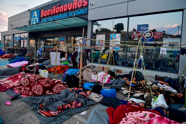 Des réfugiés et migrants dorment devant un supermarché sur la route menant à Mytilene, sur l'île grecque de Lesbos, le 12 septembre 2020, quelques jours après l'incendie qui a détruit le camp de réfugiés de Moria. (Photo LOUISA GOULIAMAKI/AFP via Getty Images)