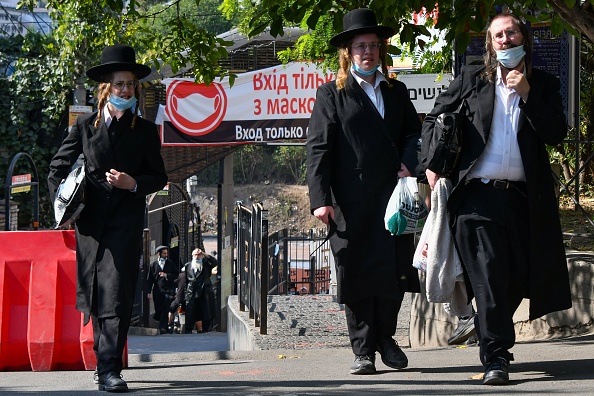 -Des juifs hassidiques portant des masques faciaux pour se protéger contre la maladie à coronavirus marchent dans la ville d'Uman, dans le centre de l'Ukraine, le 16 septembre 2020, quelques jours avant le nouvel an juif. Photo par GENYA SAVILOV / AFP via Getty Images.