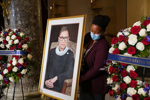 -Une employée dépose un portrait de la juge associée à la Cour suprême des États-Unis, Ruth Bader Ginsburg, avant les cérémonies au Capitole des États-Unis, où elle reposera dans l'État de Washington, DC, le 25 septembre 2020. Photo par Erin Schaff / POOL / AFP via Getty Images.