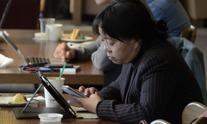 Une femme lit son téléphone et sa tablette dans un café à Pékin, le 2 novembre 2012. (WANG ZHAO/AFP via Getty Images)