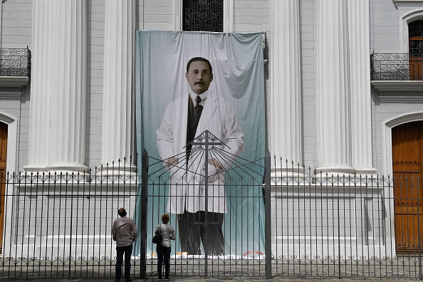 -Les gens regardent une image du médecin vénézuélien Jose Gregorio Hernandez devant l'église à Caracas, le 21 juin 2020. Photo par Federico Parra / AFP via Getty Images.