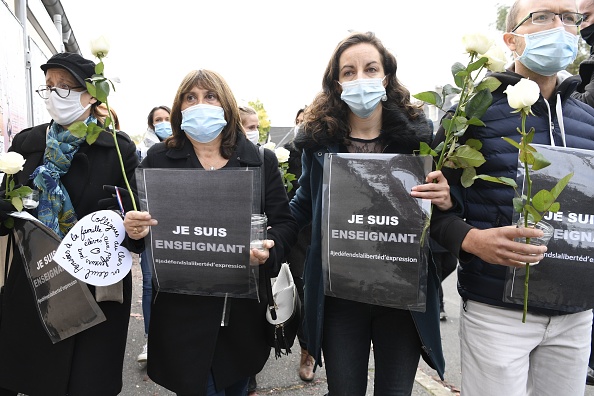 -Des gens tiennent une pancarte indiquant « Je suis enseignant - Liberté d'expression » devant un collège de Conflans-Sainte-Honorine, à 30 km au nord-ouest de Paris, le 17 octobre 2020. Photo par Bertrand Guay / AFP via Getty Images.