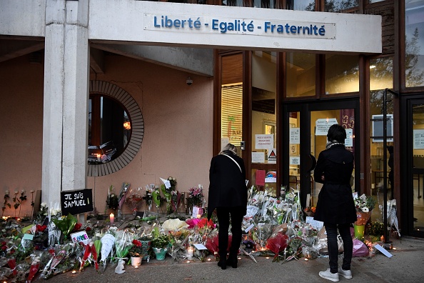 Des personnes déposent des fleurs à l'entrée du collège de Bois d'Aulne à Conflans-Sainte-Honorine, à 30 km au nord-ouest de Paris, le 17 octobre 2020. (Photo BERTRAND GUAY/AFP via Getty Images)