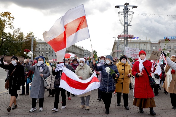 -Des retraités biélorusses portant d'anciens drapeaux blanc-rouge-blanc de la Biélorussie et des fleurs défilent dans les rues lors d'un rassemblement pour exiger la démission du dirigeant autoritaire et de nouvelles élections justes. Photo par Stringer / AFP via Getty Images.