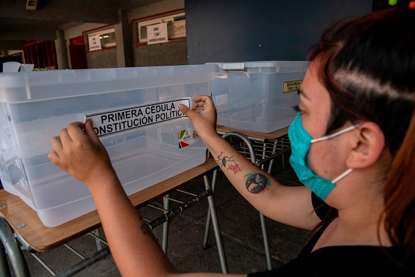 -Un employé du service électoral du Chili met en place un bureau de vote à la veille d'un référendum constitutionnel national voté à Santiago, le 24 octobre 2020. Photo par Martin Bernetti / AFP via Getty Images.