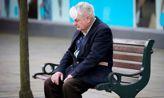 Un homme portant un masque se repose sur un banc pendant la pandémie du virus du PCC à Oldham, en Angleterre, le 29 juillet 2020. (Christopher Furlong/Getty Images)