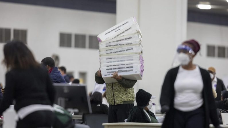 Un employé du département des élections de Détroit transporte des boîtes vides utilisées pour organiser les votes par correspondance après la fin du décompte des votes par correspondance au bureau central de décompte du centre TCF de Détroit, Michigan, le 4 novembre 2020. (Elaine Cromie/Getty Images)